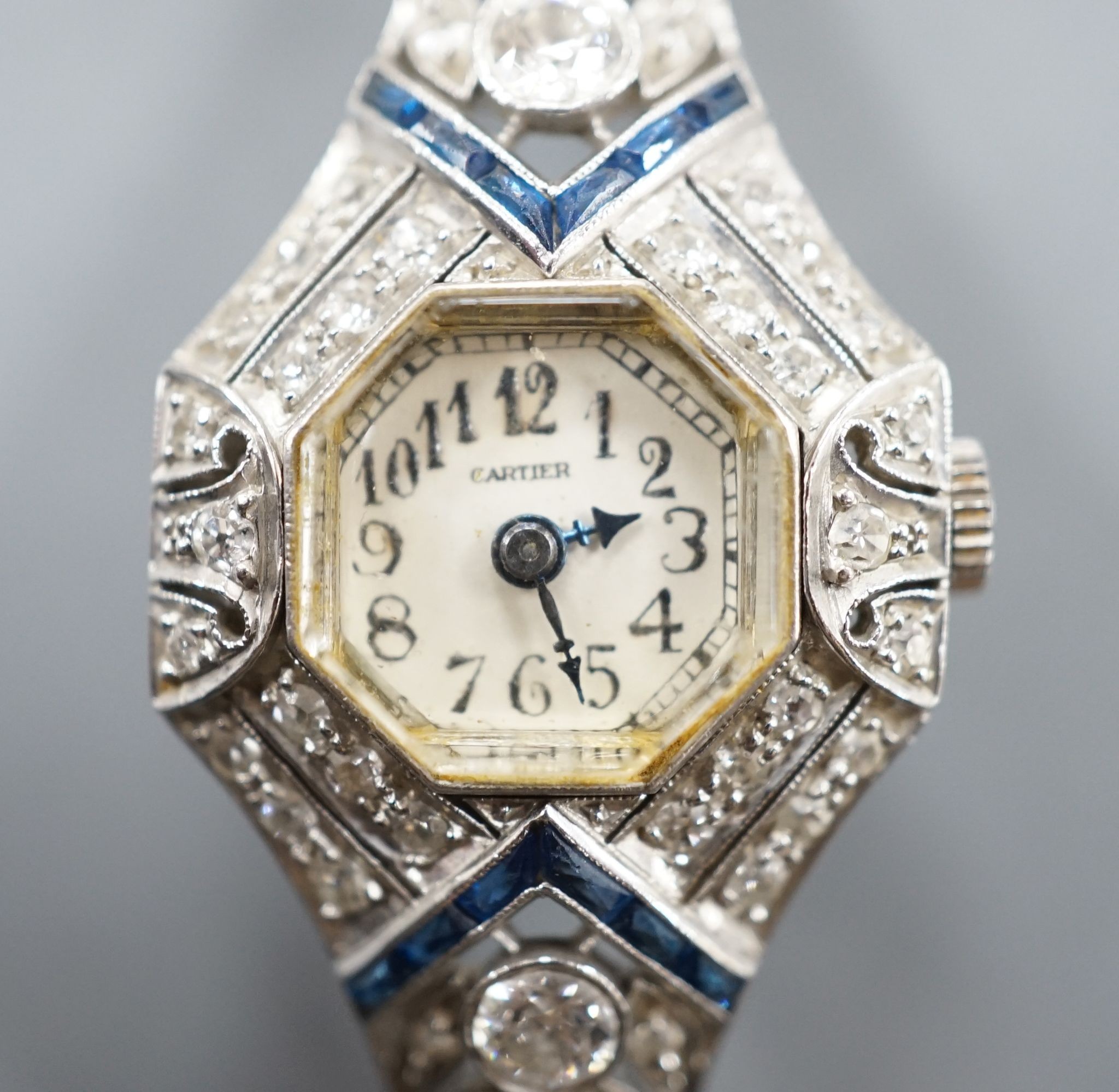 A mid 20th century white metal, synthetic sapphire? and diamond set cocktail watch, with Bucherer manual wind movement and dial bearing the signature Cartier, on a 14k white metal bracelet, case diameter 22mm, gross weig